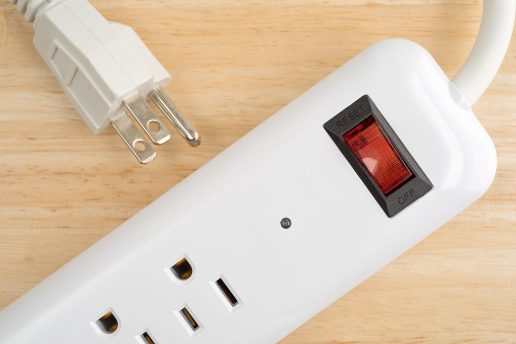 Top close view of a household surge protector on a wood table top.